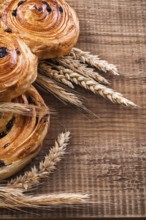 Ripe wheat ears rich rolls with raisins on oaken wooden board food and drink concept