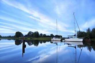 Two yachts on river during calm morning with beautiful cloudscape