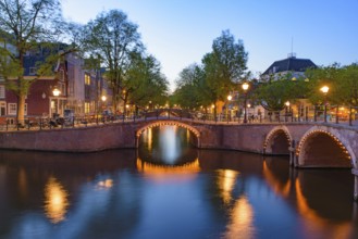 Reflection of bridge along the canal at night in Amsterdam, Netherlands