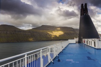 Blue sun deck of a ferry with the coast of the Faroe Islands in the background
