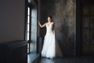 Portrait of beautiful young woman on dark background near the window