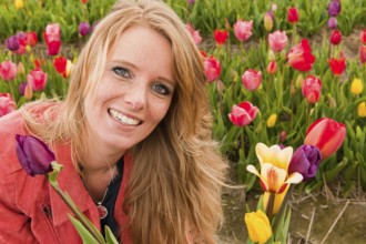 Young blond woman is picking tulips in Dutch flower fields