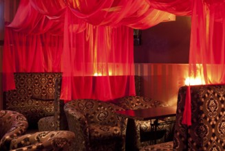 Restaurant interior (oriental style) - soft sofas and red transparent curtains
