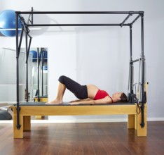 Pregnant woman pilates reformer shoulder bridge exercise workout at gym