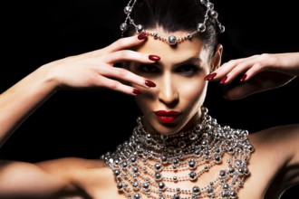 Beautiful woman with dark makeup wearing blue and silver mask surrounded by party accessories on
