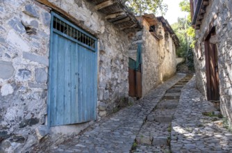 Stoned footpath crossing a traditional village. Stoned houses with wooden doors. Vintage