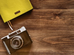 Top view vintage old camera and notebook on wooden background