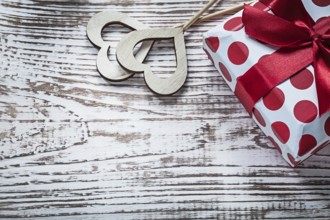 Present box with tied red bow wood hearts on vintage wooden board holidays concept