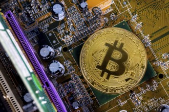 Virtual cryptocurrency money Bitcoin golden coin on a computer printed circuit board PCB. The
