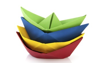 Stacked colorful folded paper boats isolated over white background