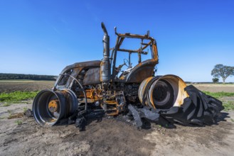 Fully destroyed burnt down tractor on a field