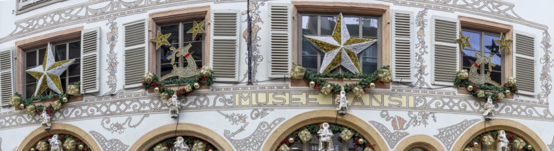 Panoramic photo of a shop front decorated for Christmas with many Father Christmases in golden