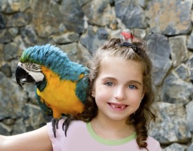Blue eyes child girl with yellow parrot in her shoulder