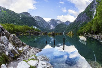 The boat is reflected in the clear water of the lake. Gorgeous Norway. Emerald green of summer