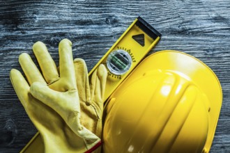 Construction level safety gloves building helmet on wooden board