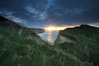 Sunset sunshine over cliffs in ocean, Normandy, France, Europe