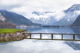 Trip idea theme image with the Hallstatter lake, a small bridge that crosses it and the majestic