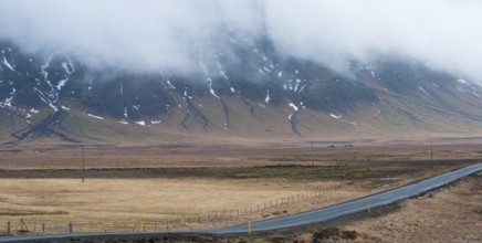 Rural empty straight road with mountains covered in fog at in Reykjanes peninsula in Iceland