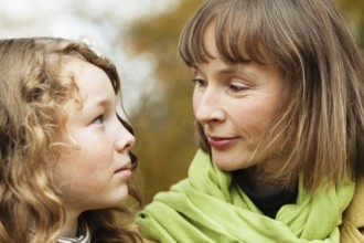 Mother and teenager daughter looking at each other while walking in an autumn park, Belgium, Europe