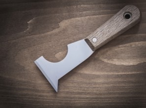 Stainless putty spattle on vintage wooden board construction concept