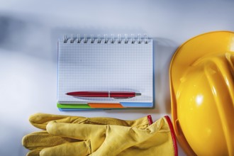 Protective gloves building helmet notepad pen on white background