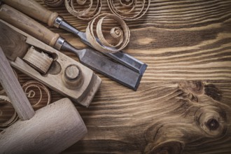 Flat chisels shaving plane curled shavings lump hammer on wooden board construction concept