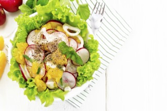 Radish, onion and orange salad with mint, vegetable oil and spices on lettuce in a plate on a towel
