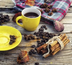 Yellow cup of black coffee on background with autumn leaves