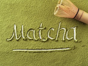 Matcha word over green matcha tea powder background and bamboo whisk Chasen. Top down view or flat