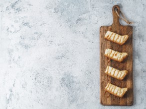 Caramelized cheesecake slices on wooden cuttingboard. Cheesecake on gray cement background with