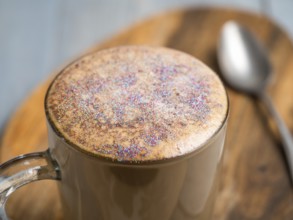 Trendy Coffee with edible glitter. Cup of sparkly coffee or diamond cappuccino on gray table. Copy