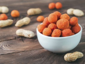 Peanut snack for beer, wine, party bar. Salted peanuts in red spicy chilli glaze on brown wooden