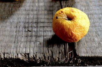 Wrinkled yellow apple on a wooden board