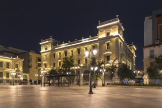 A picture of a yellow building on the Kotzia Square, at night