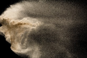 Dry river sand explosion. Golden colored sand splash against black background