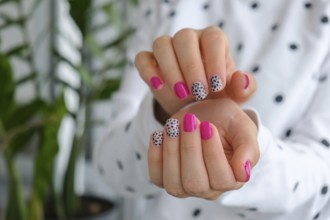 Manicured female hands with stylish pink nails and design. Trendy modern design manicure. Gel nails