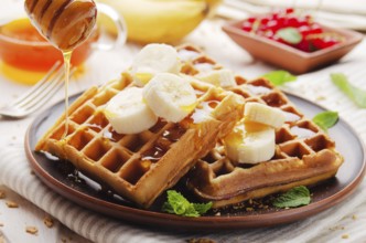 Homemade crispy Belgian waffles served with banana and honey