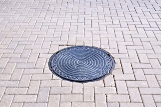 The road of brown tiles with a round metal hatch