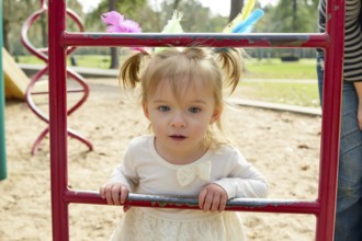 Kid girl and mother playing with playground ladder in the park