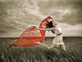 Brunette girl jumping with red fabric in summer day. Outdoors potrait