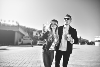 Smiling couple walk at the street in weekend and drink some cocktails