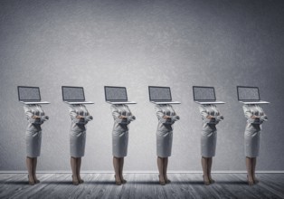 Business women in suits with laptop instead of their heads keeping arms crossed while standing in a