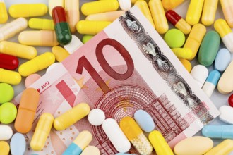 Euro banknotes and tablets, symbolic photo for costs of medication and health insurance. Austria