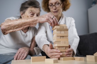Senior woman practice skills, build wooden blocks, build tower and try not to let it fall, Jenga