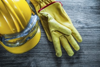 Safety gloves hard hat goggles on vintage wooden board