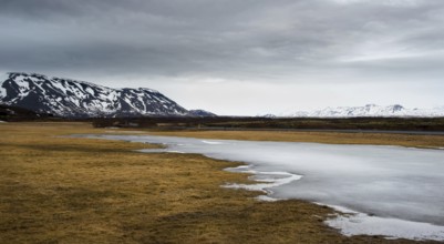Typical Icelandic dramatic landscape with frozen lake and mountains covered in snow in Iceland
