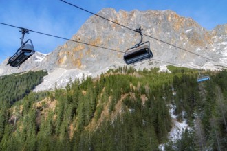 Alpine scenery with the rocky peaks of the Alps mountains and ski lifts rolling on a cableway over