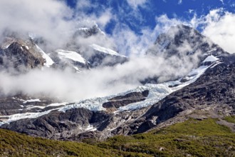 Impressive snow-covered peaks under a clear sky, framed by dramatic clouds, the glaciers of the