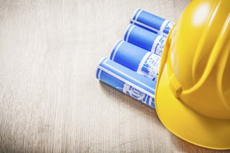 Wooden board with blue rolled construction drawings safety helmet