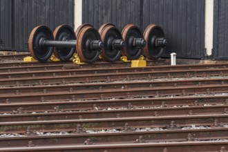 Several railway wheels are lined up next to each other on the rails in front of a building, bochum,